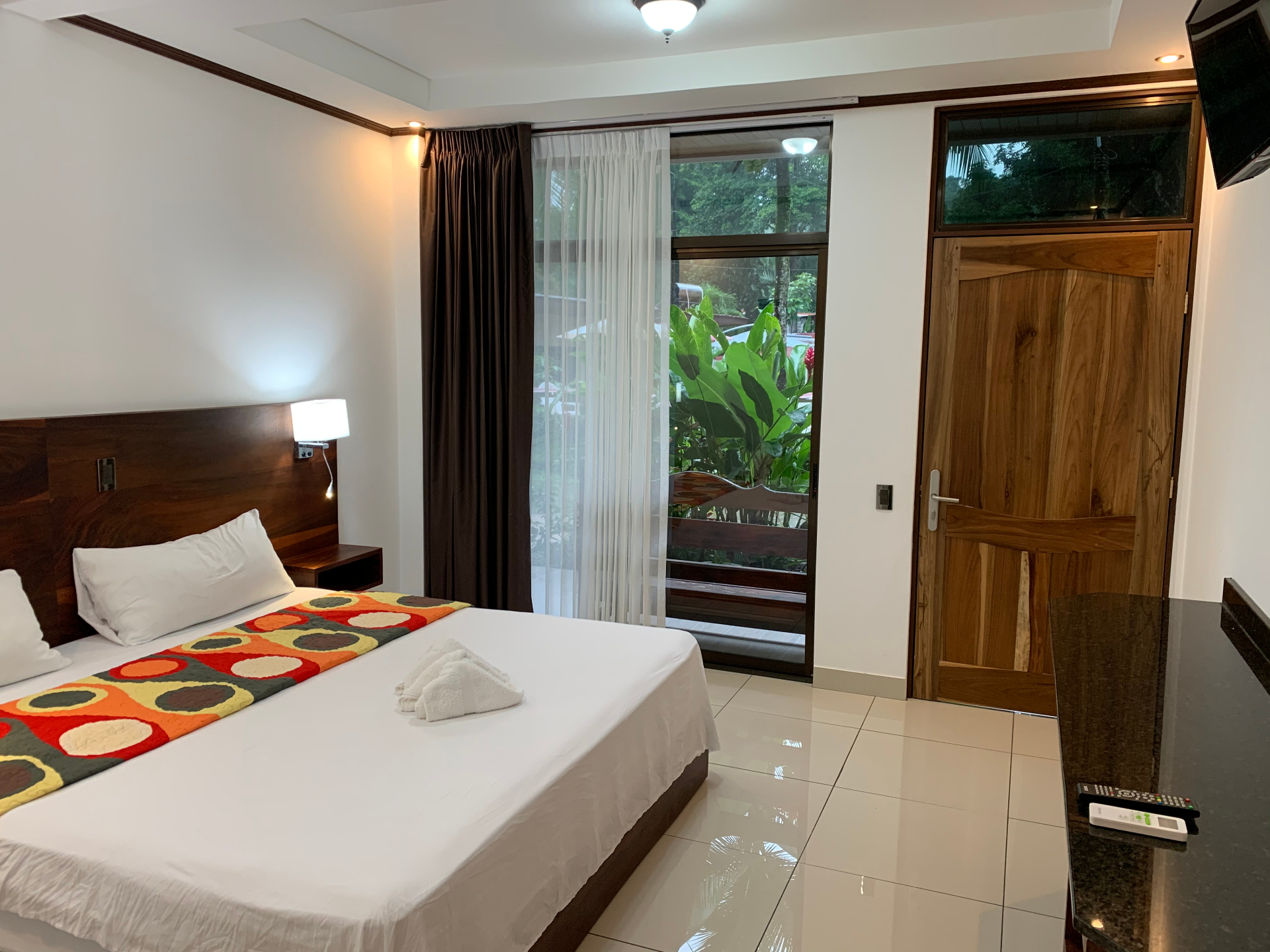 Habitación Deluxe King con cama king size, cabecero de madera y terraza a la selva